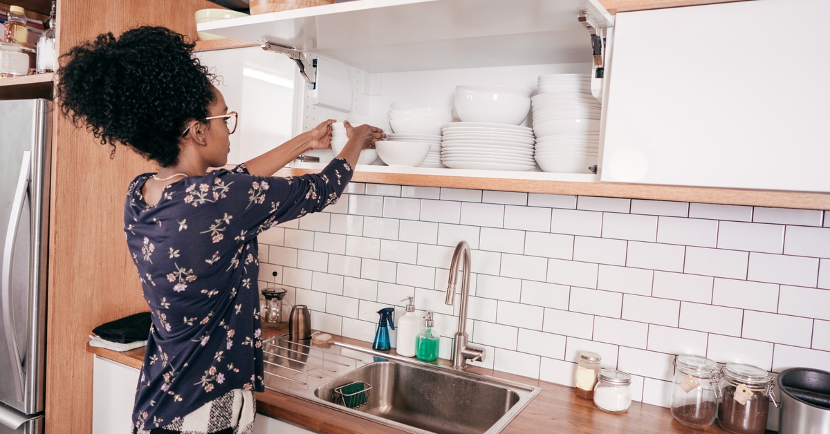 mulher arrumando armário da cozinha