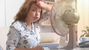 mulher com calor em frente a ventilador